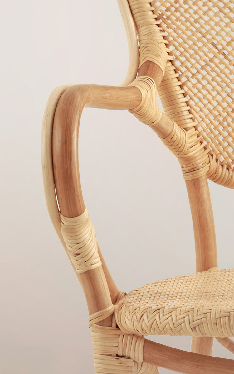 Esta es una imagen de detalle de Rossini sillón de comedor en natural rattan. Detalle de la curva del reposabrazos de ratán claro y asiento de espiga.