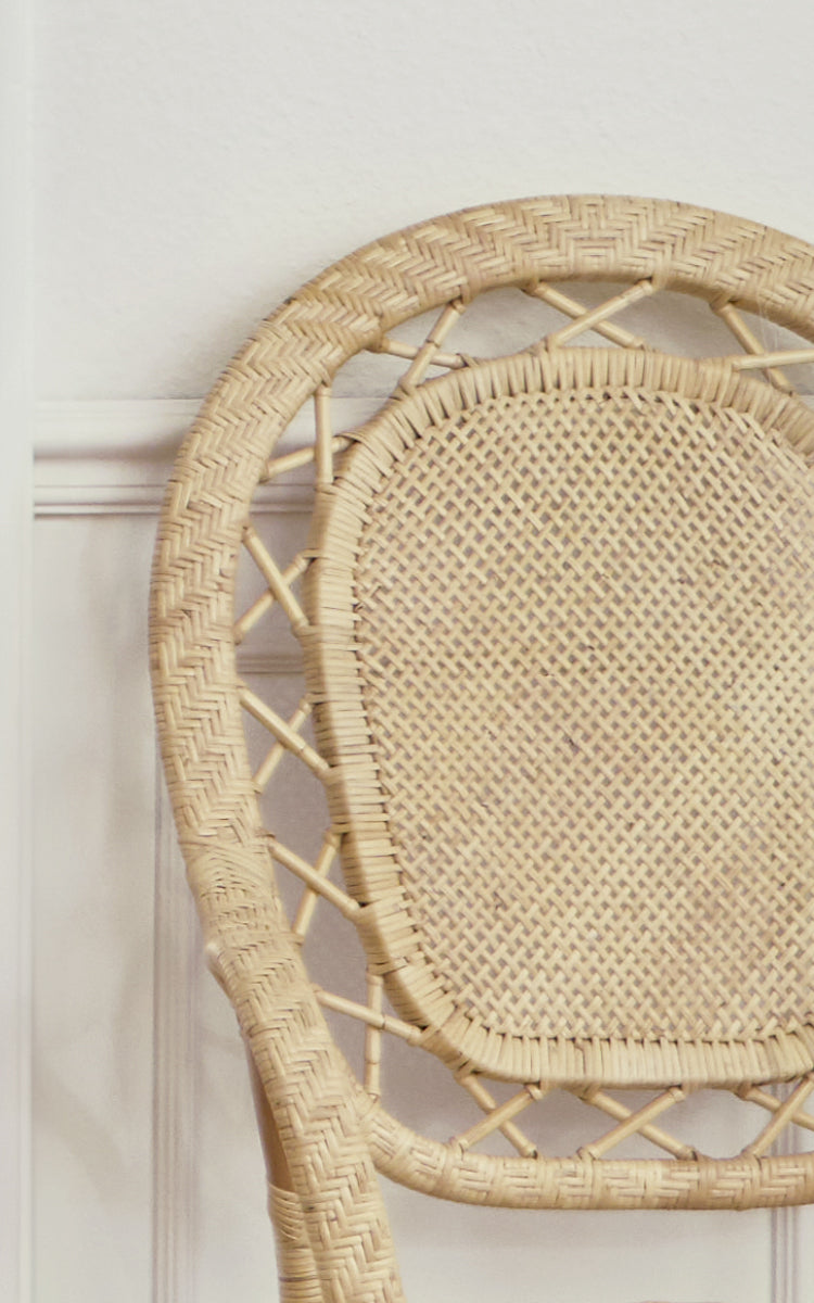 Esta es una imagen de detalle de Romantica silla de comedor en natural rattan. El respaldo redondo presenta un borde tejido en espiga y centro de rejilla.