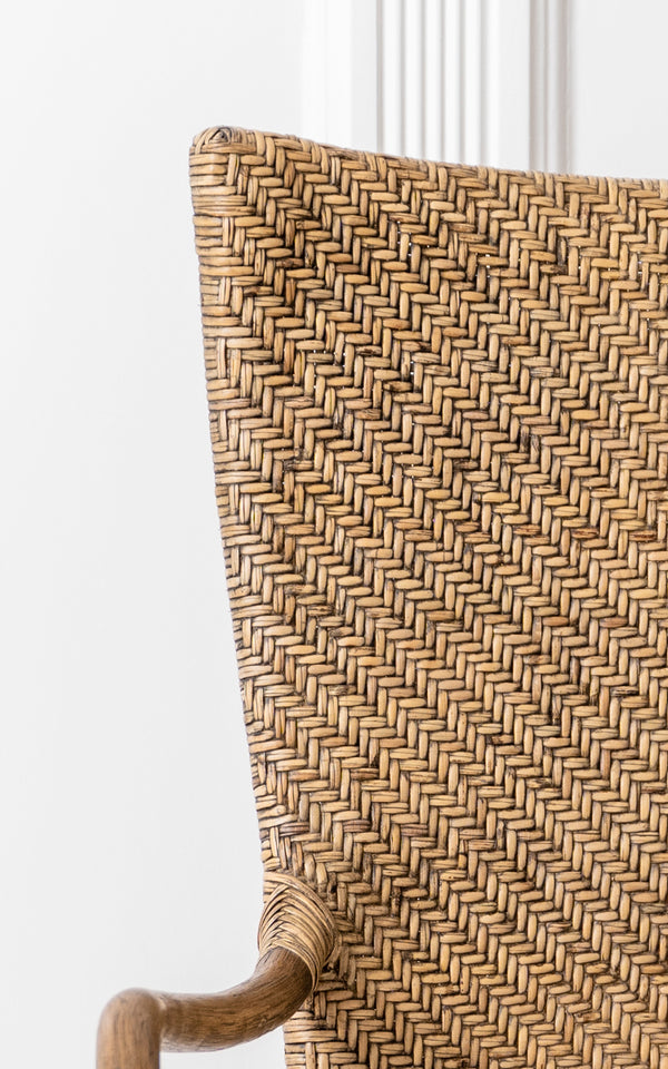 Esta es una imagen de detalle de Melody Dining Armchair i antique rattan. Detalle del respaldo con tejido de espiga y el reposabrazos curvado de ratán.