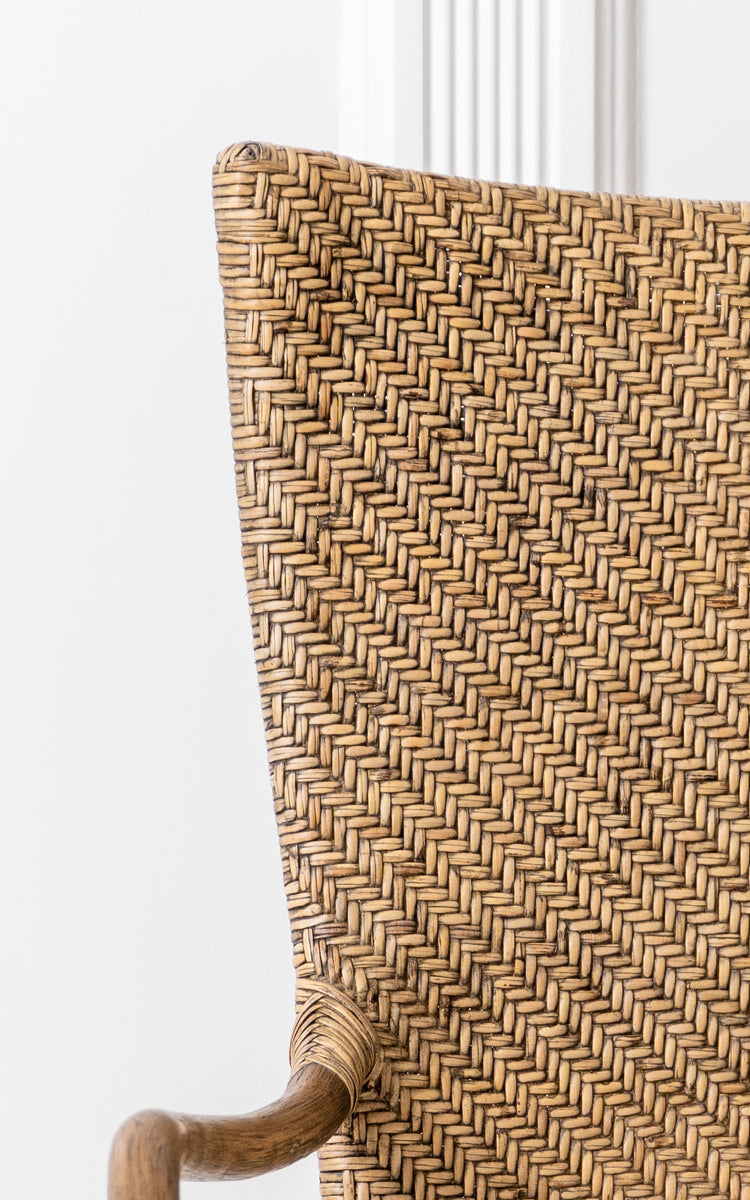 Esta es una imagen de detalle de Melody Dining Armchair i antique rattan. Detalle del respaldo con tejido de espiga y el reposabrazos curvado de ratán.