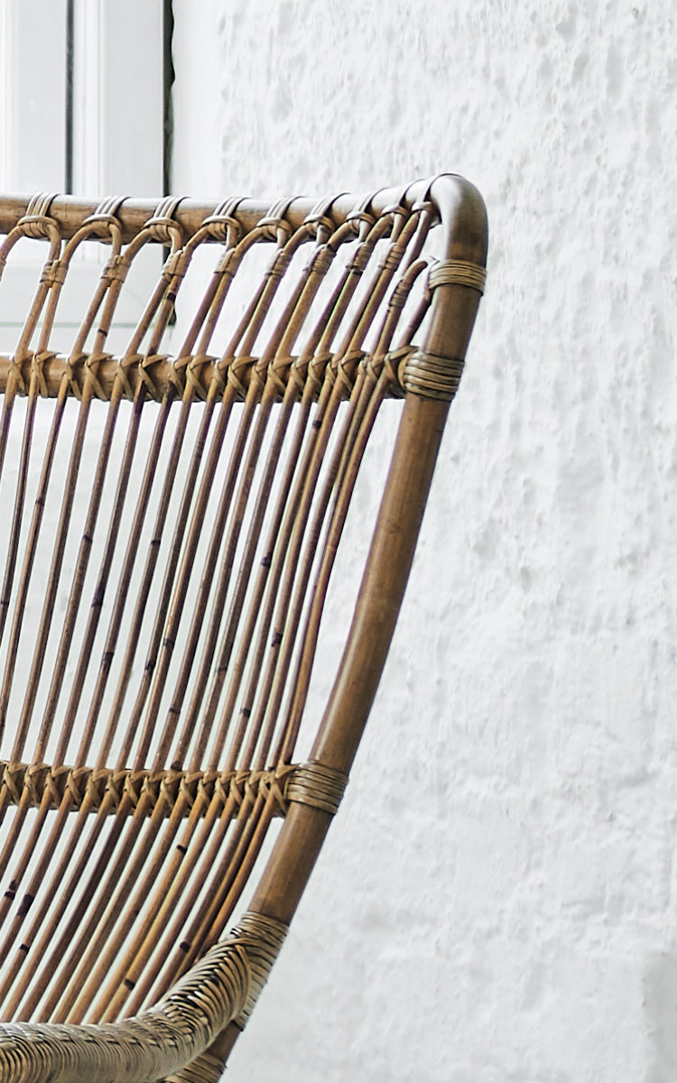 Esta es una imagen de detalle de Monet Lounge Chair i antique rattan. Detalle del respaldo de arcos en bucle con varillas verticales y asiento tejido.