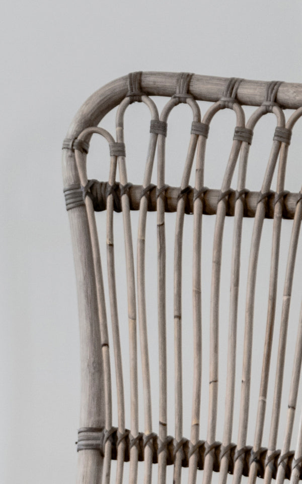 Esta es una imagen de detalle de Monet Lounge Chair i taupe rattan. Detalle del diseño de arcos en bucle y varillas verticales en tono taupe cálido.