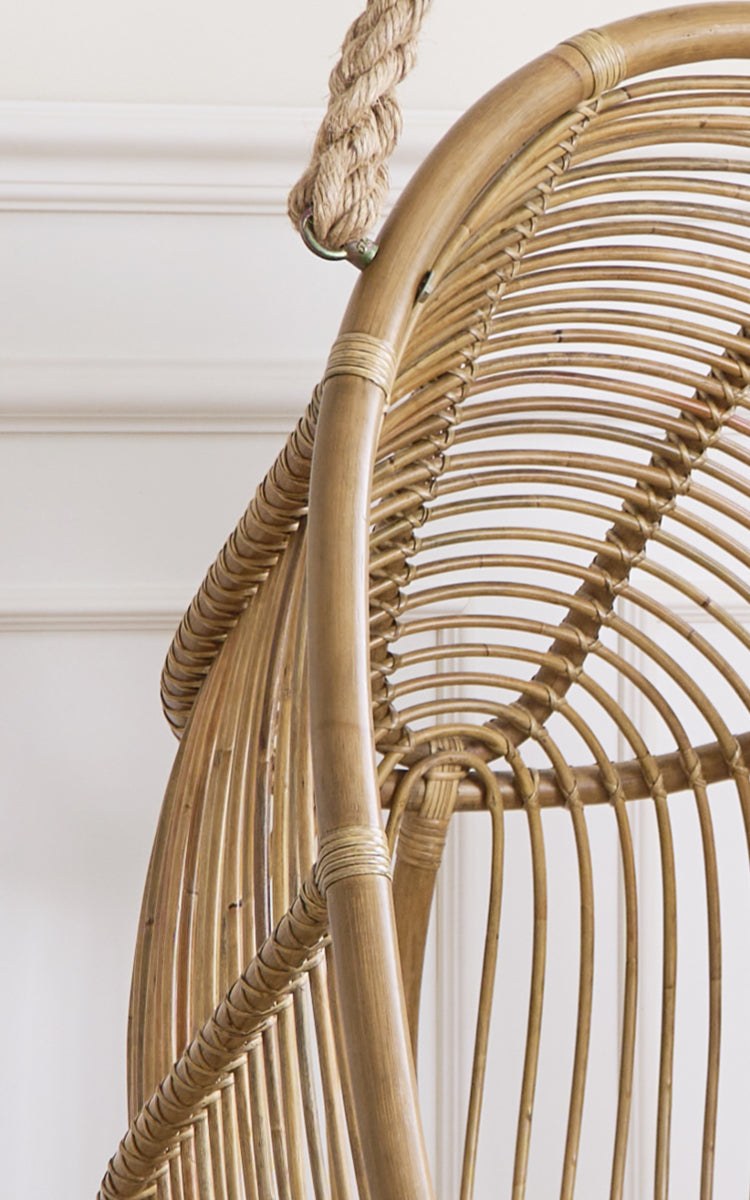 Esta es una imagen de detalle de Renoir silla colgante en antique rattan. Detalle de la estructura curva de ratán con radios y colgador de cuerda.
