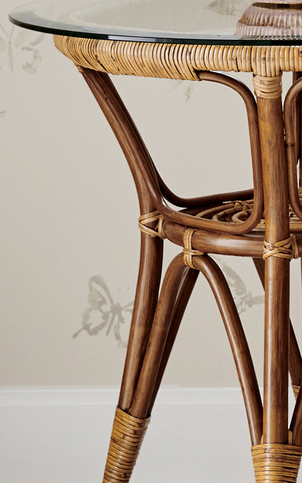 Esta es una imagen de detalle de Tony mesa auxiliar en antique rattan. Detalle del borde del tablero de vidrio con ratán envuelto y patas curvas.