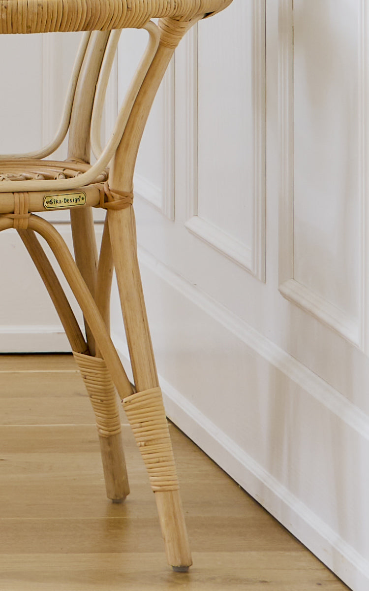 Esta es una imagen de detalle de Tony Side Table i natural rattan. Detalle del borde de la tapa de cristal y la construcción del marco de ratán envuelto.