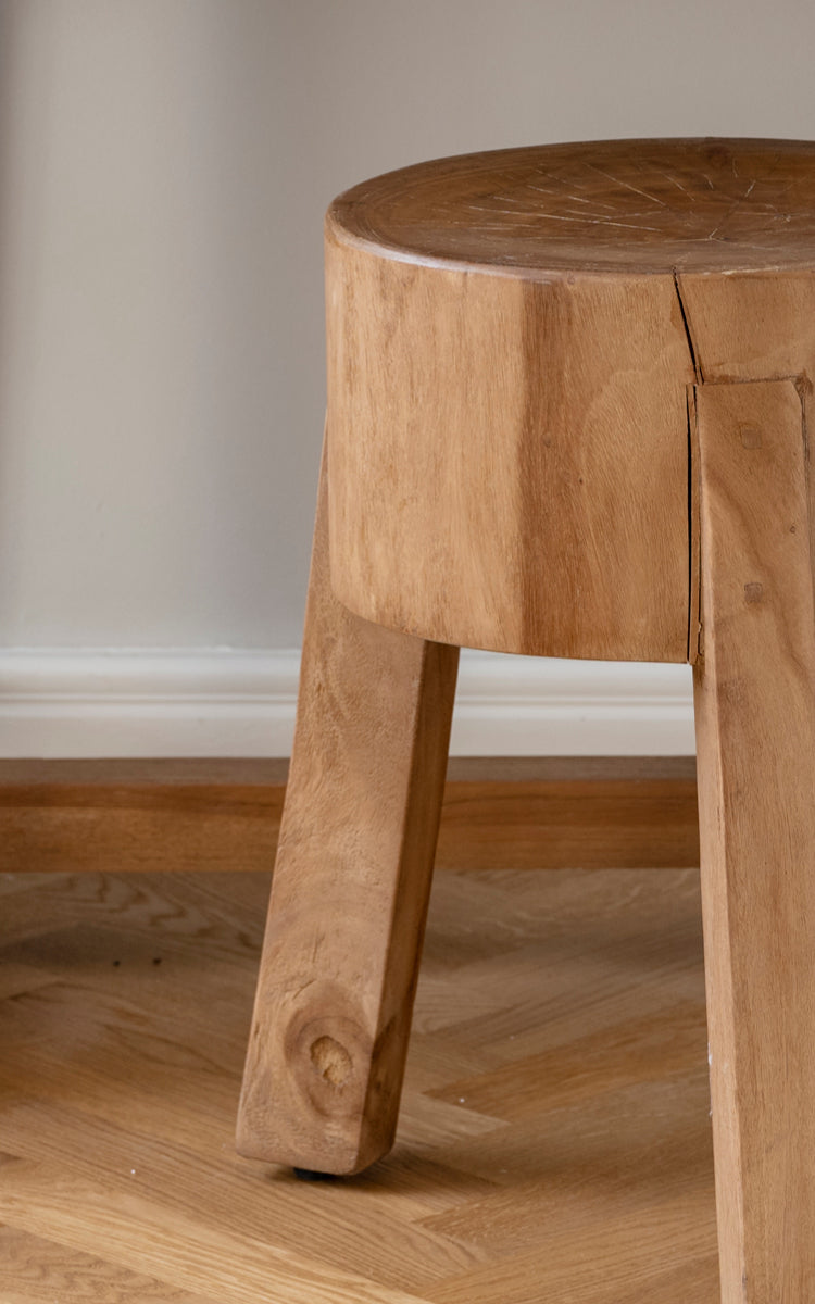 Esta es una imagen de detalle de Roger taburete en teak indoor. Detalle del asiento macizo de teca y tres patas angulares robustas.
