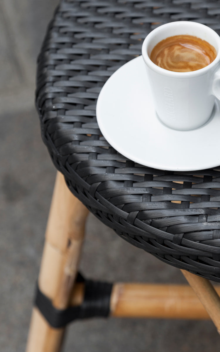 Esta es una imagen de detalle de Simone taburete alto en black ArtFibre Skin on Rattan frame. Detalle del asiento tejido con una taza de espresso.