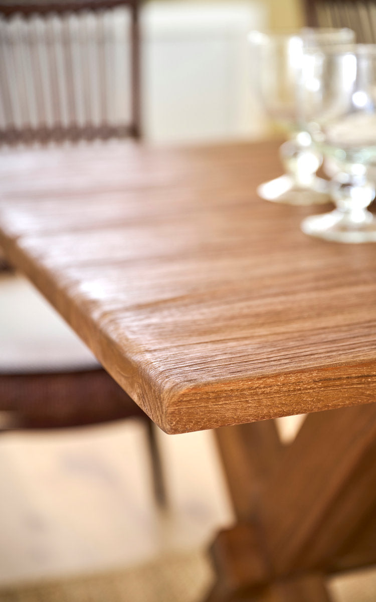 Esta es una imagen de detalle de Hugo mesa de comedor de teca 180x90 cm en teak indoor. Borde de la tapa de teca con copas y sillas de ratán.