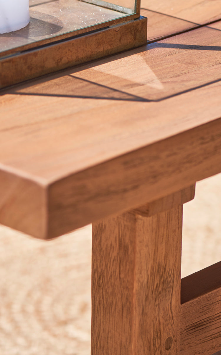 Esta es una imagen de detalle de Julian Teak Lounge Table 140x55 cm en teak outdoor. El grueso borde de teca maciza y las uniones robustas de las patas se muestran.