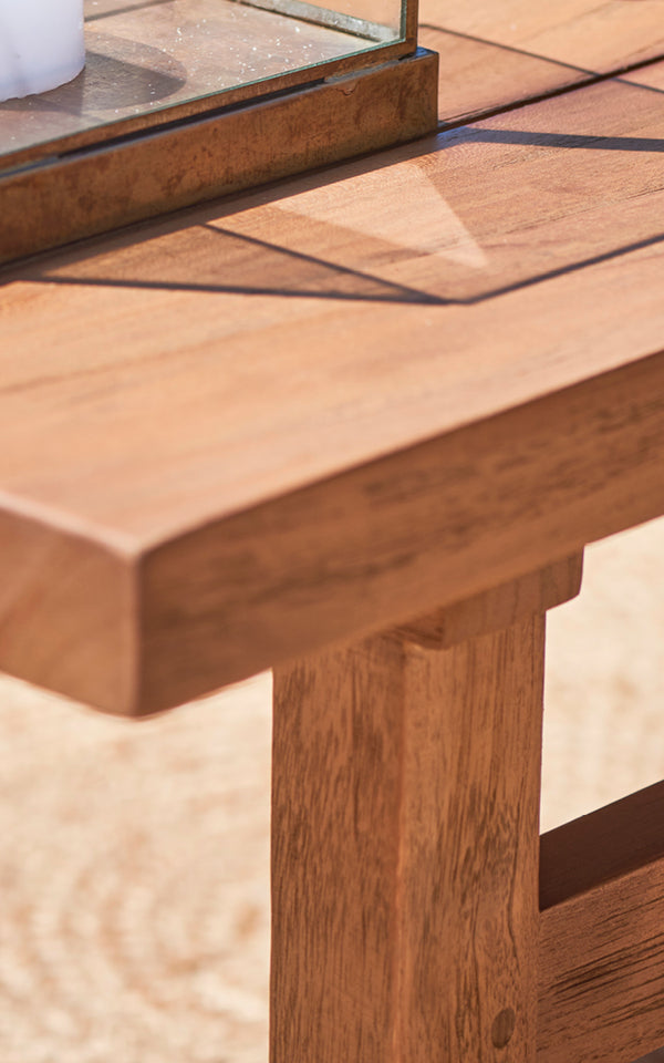Esta es una imagen de detalle de Julian Teak Lounge Table 120x120 cm en teak outdoor. La superficie de teca maciza y el borde grueso se muestran bajo cálida luz solar.