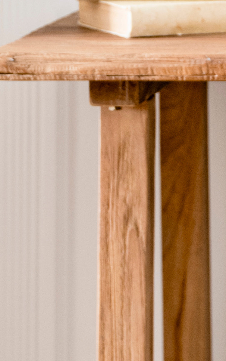 Esta es una imagen de detalle de Lucas Teak escritorio en teak indoor. El borde de teca maciza y las patas anguladas revelan la veta cálida y la construcción robusta.