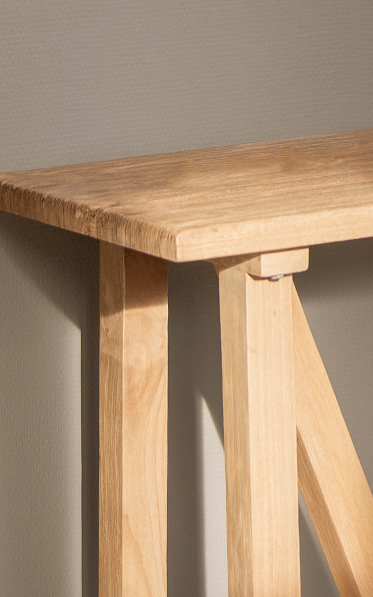 Esta es una imagen de detalle de Lucas Teak consola en teak indoor. La superficie de teca maciza y las patas en caballete muestran líneas limpias y tonos de madera.
