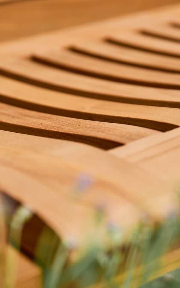 Esta es una imagen de detalle de St Catherine banco de teca en teak outdoor. Detalle de los listones curvos de teca de la superficie del asiento del banco.