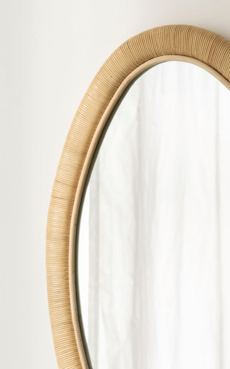 Esta es una imagen de detalle de Malou espejo en natural rattan. Marco de ratán envuelto con forma ovalada orgánica y luz suave.