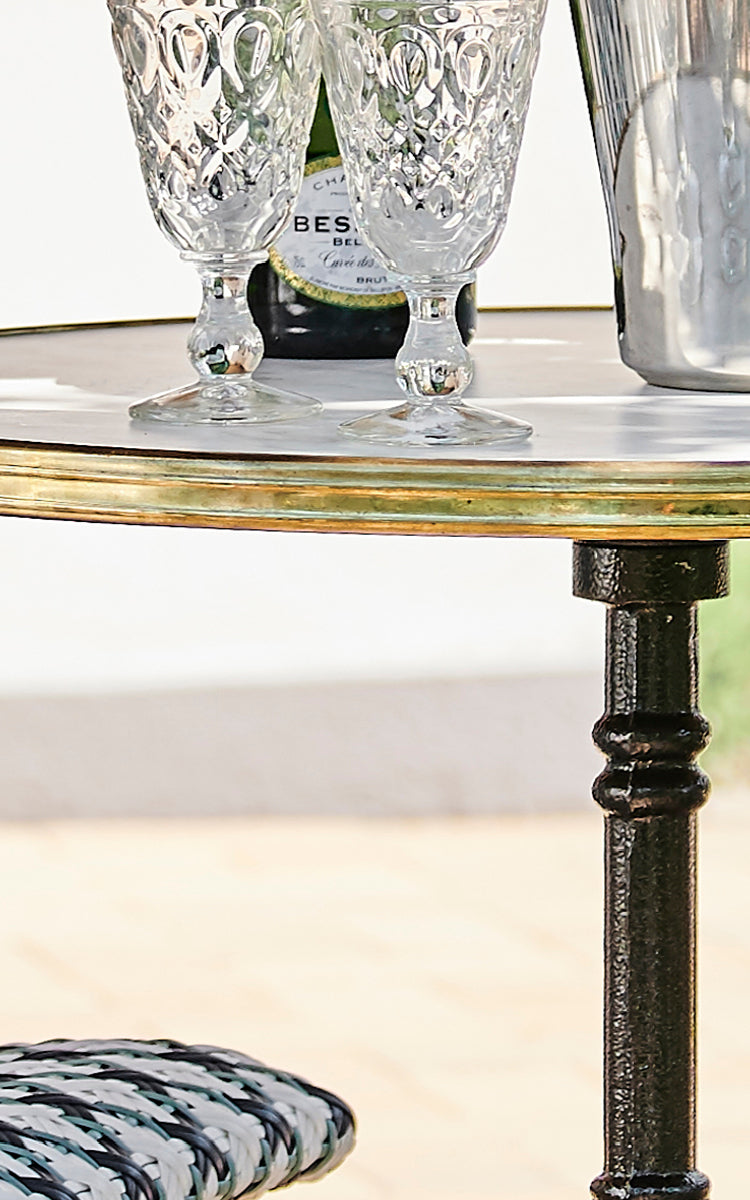 Esta es una imagen de detalle de Lyon mesa de café Versalite Marble Ø70 cm en cast iron. Borde de mármol con aro de latón y pedestal de hierro ornamentado.