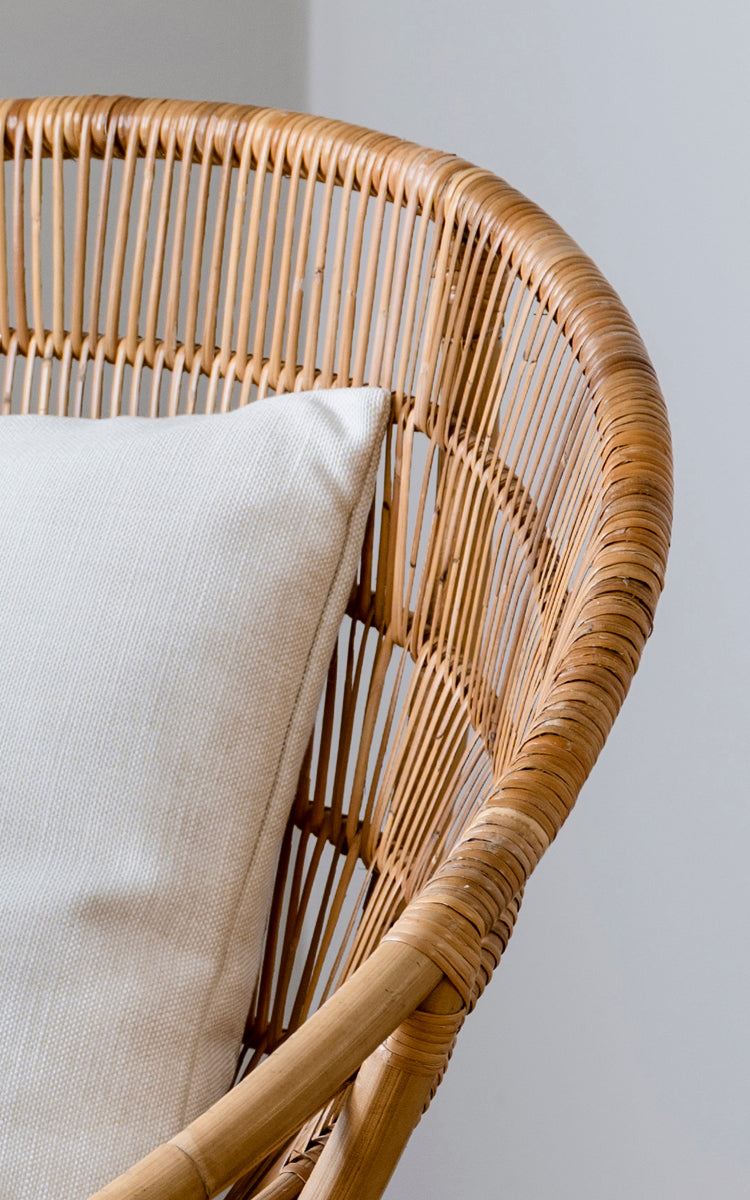 Esta es una imagen de detalle de Luna sillón lounge en natural skin on rattan. El marco curvado con listones verticales y cojín blanco destacan el diseño.