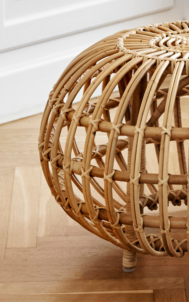 Esta es una imagen de detalle de Ottoman Small en natural skin on rattan. Detalle de la jaula de ratán abierta con costillas curvas y atados cruzados.