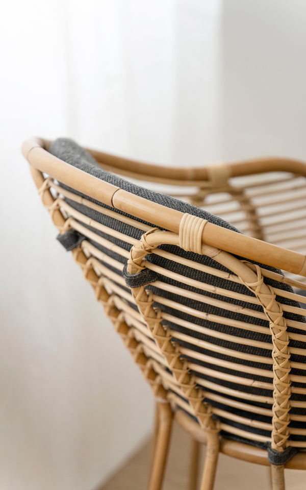 Esta es una imagen de detalle de Swing sillón lounge en polished natural rattan. Detalle del travesaño curvo de ratán y atado trenzado del respaldo.