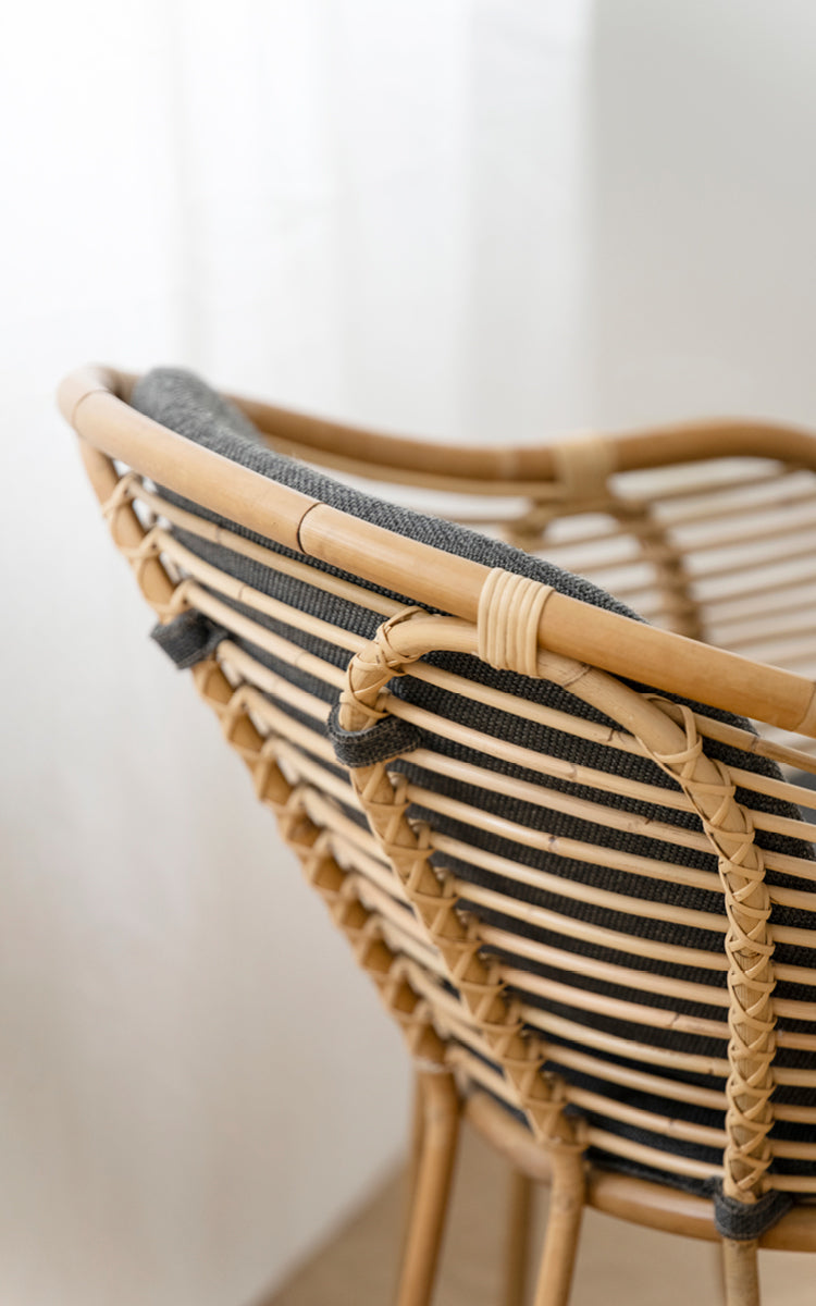 Esta es una imagen de detalle de Swing sillón lounge en polished natural rattan. Detalle del travesaño curvo de ratán y atado trenzado del respaldo.