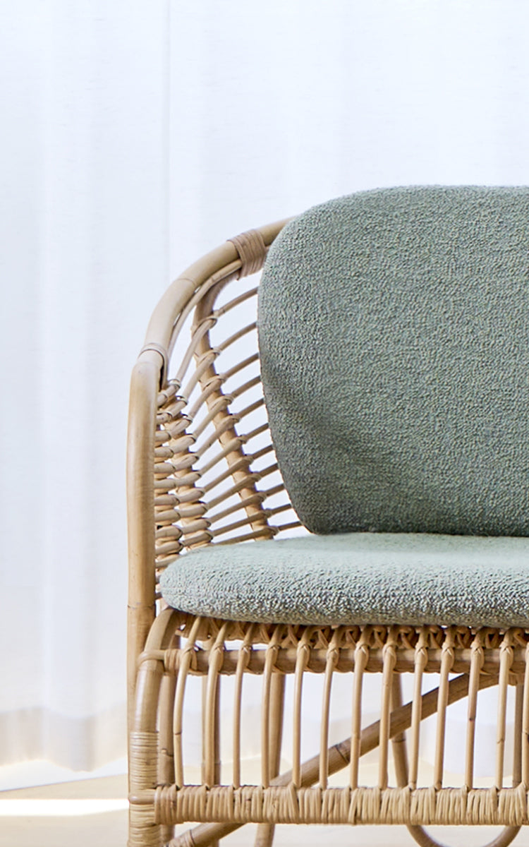 Esta es una imagen de detalle de Swing sofá en polished natural rattan. Detalle de la estructura curva de ratán del sofá con cojín de asiento bouclé.