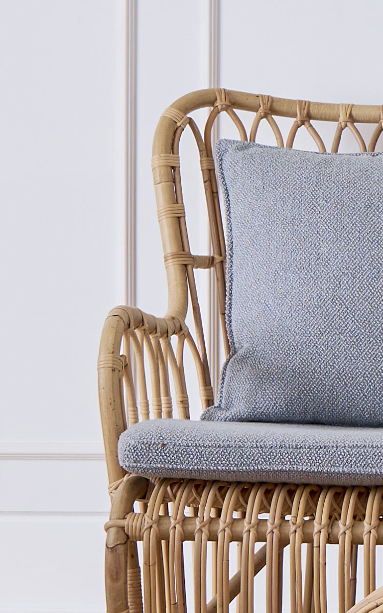 Esta es una imagen de detalle de Tulip sofá en polished natural rattan. Detalle de la estructura de ratán del sofá con refuerzos arqueados y cojín bouclé.