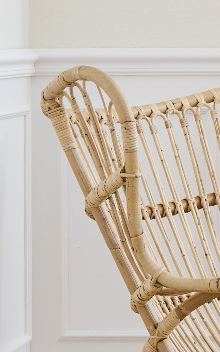 Esta es una imagen de detalle de Teddy sillón lounge en polished natural rattan. Detalle del travesaño curvo de ratán y respaldo de husillos.