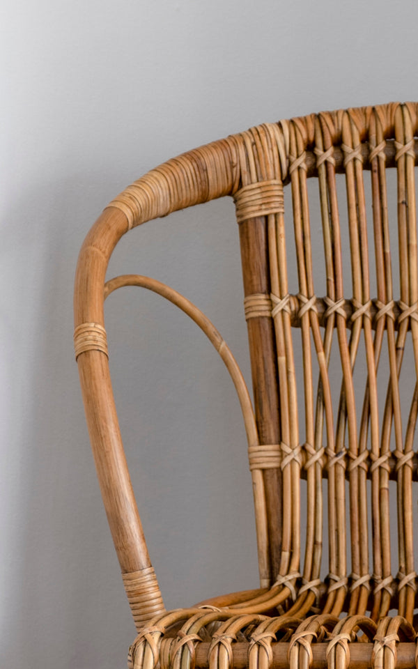 Esta es una imagen de detalle de Robert silla de comedor en polished antique rattan. Detalle del brazo curvo de ratán y respaldo de husillos con uniones envueltas.