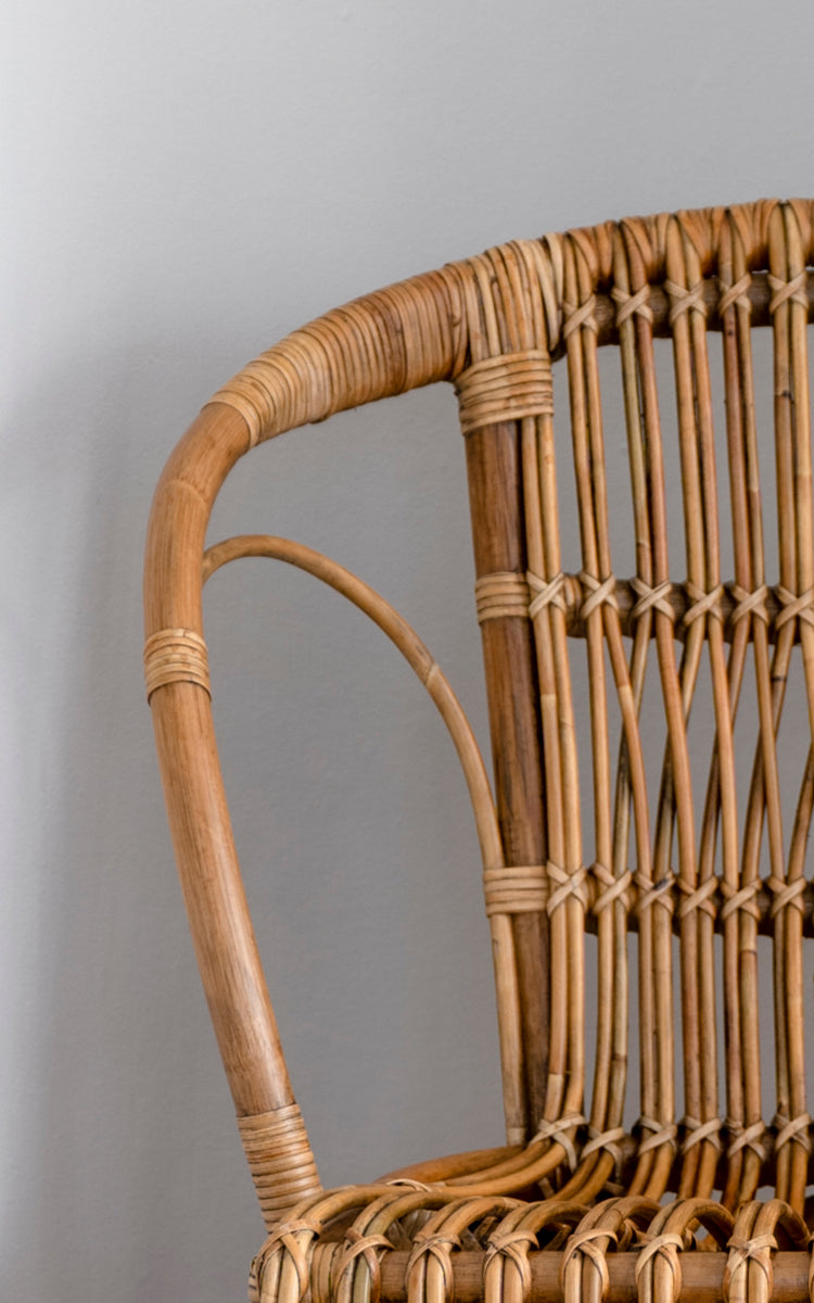 Esta es una imagen de detalle de Robert silla de comedor en polished antique rattan. Detalle del brazo curvo de ratán y respaldo de husillos con uniones envueltas.