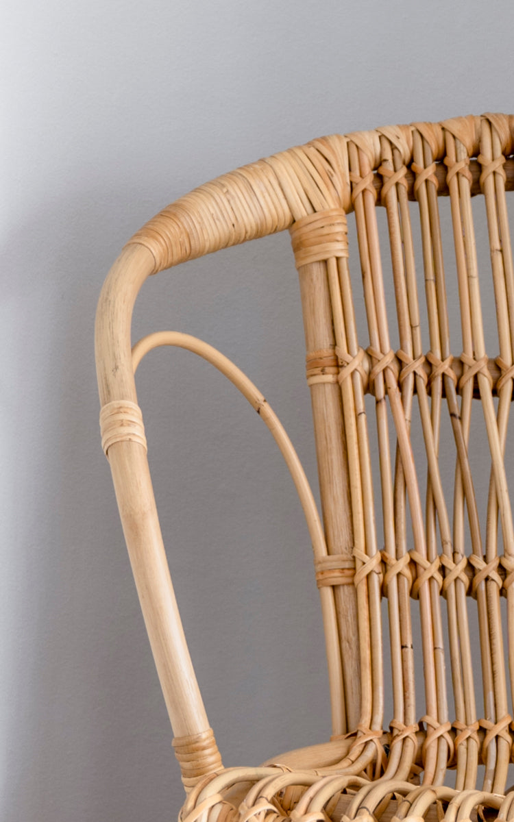 Esta es una imagen de detalle de Robert silla de comedor en polished natural rattan. Detalle del brazo curvo natural de ratán y respaldo de husillos.