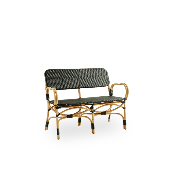 Vista lateral del banco Bistro en tejido ArtFibre negro con diseño elegante. Estructura de ratán con asiento tejido en ArtFibre. La estructura curva de ratán bajo el asiento se extiende hasta formar los reposabrazos.