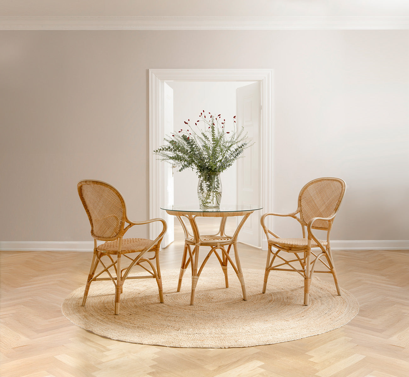 Esta es una imagen de estilo de vida de Rossini Dining Armchair en natural rattan. Estilizado en un interior luminoso.