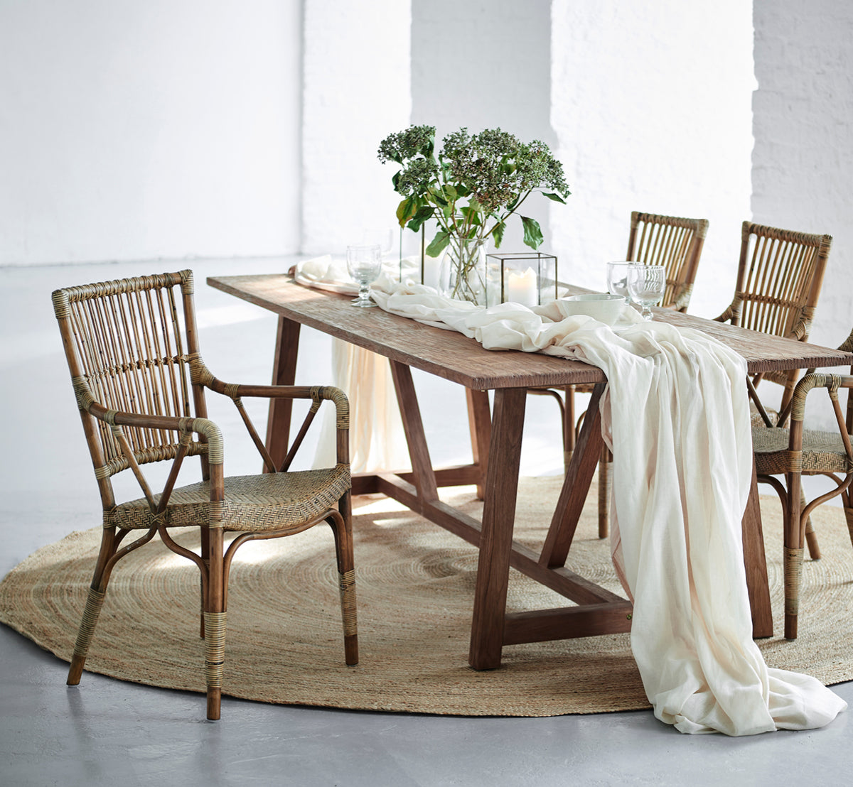 Esta es una imagen de estilo de vida de Piano silla de comedor en antique rattan. Alrededor de una mesa rústica de madera con camino de lino y velas.