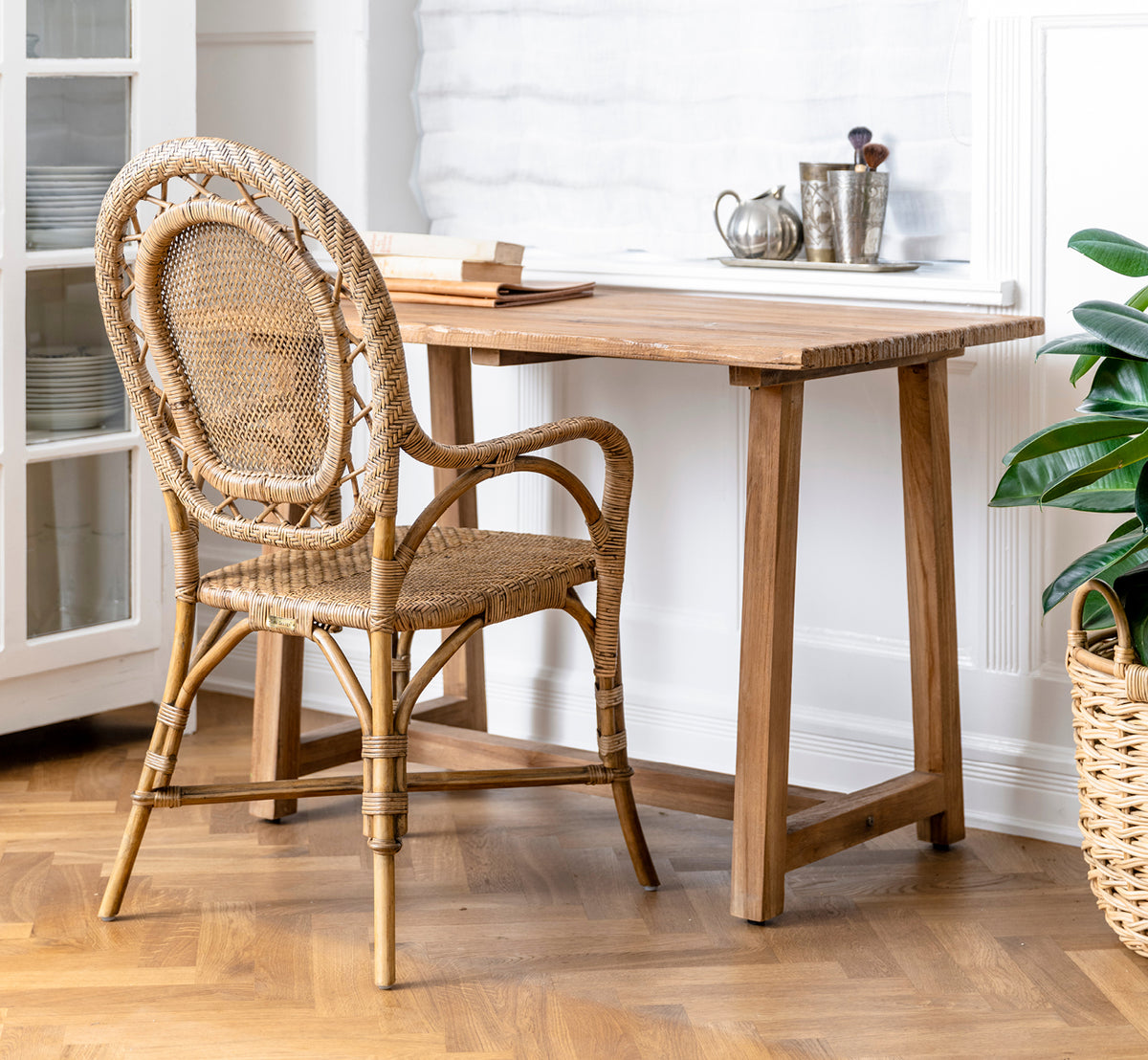 Esta es una imagen de estilo de vida de Romantica silla de comedor en antique rattan. Dispuestas en un nicho interior de piedra gris con lámparas de pared de hierro forjado.