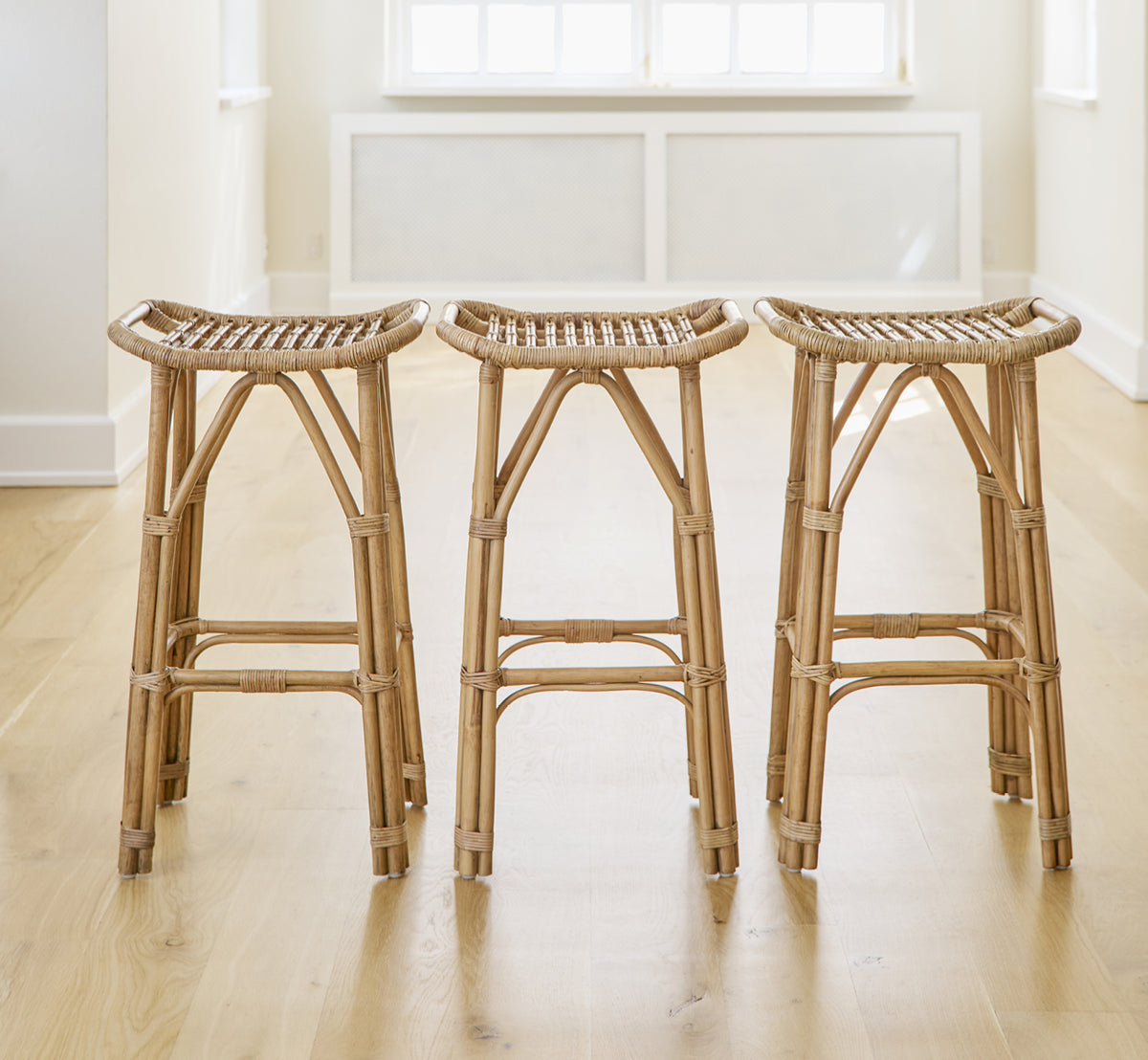 Esta es una imagen de estilo de vida de Salsa taburete de bar en antique rattan. Un par colocadas contra una pared blanca sobre suelo de parqué en espiga.