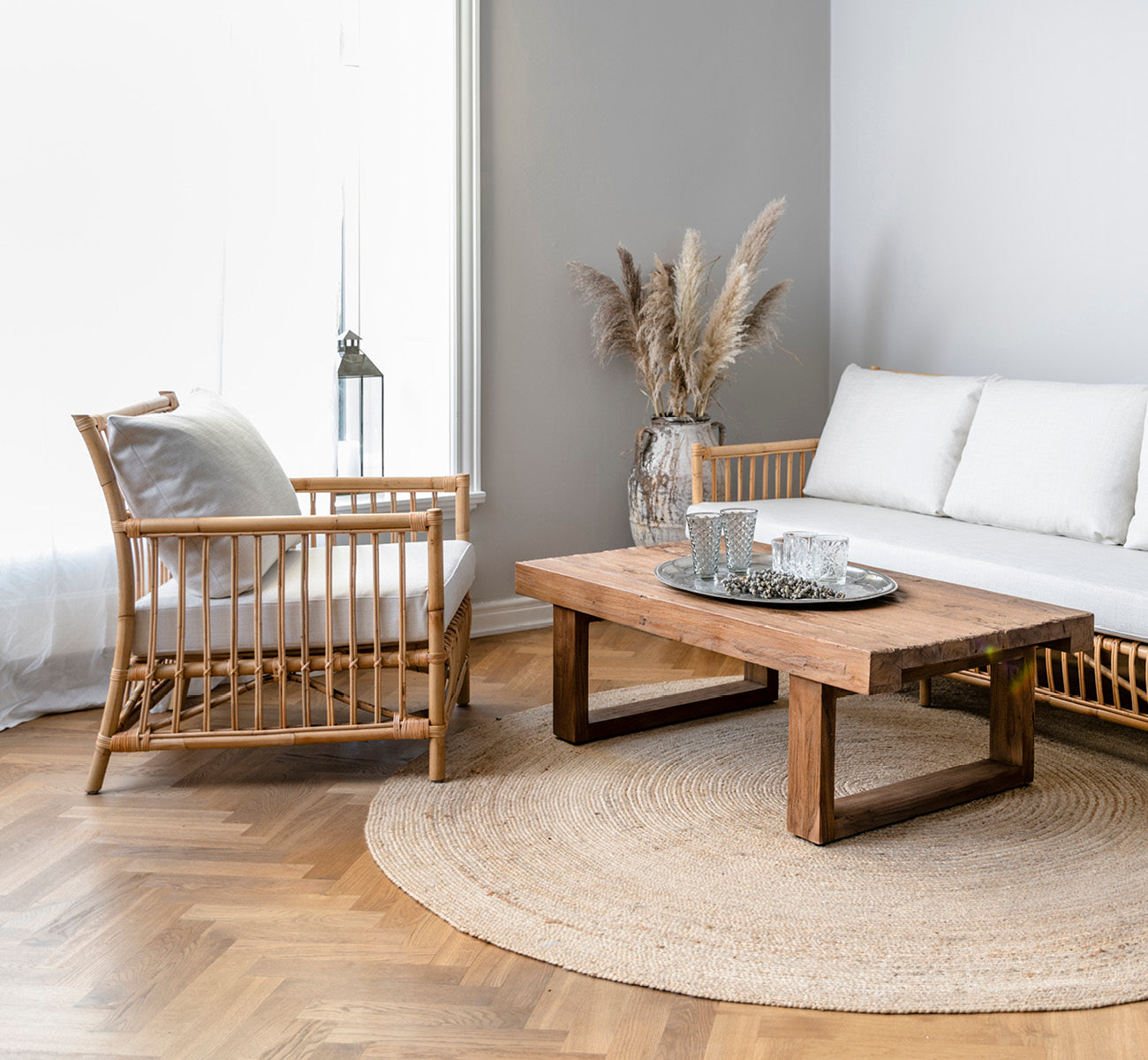 Esta es una imagen de estilo de vida de Caroline sillón lounge en natural rattan, en una luminosa sala de estar escandinava con parqué en espiga.