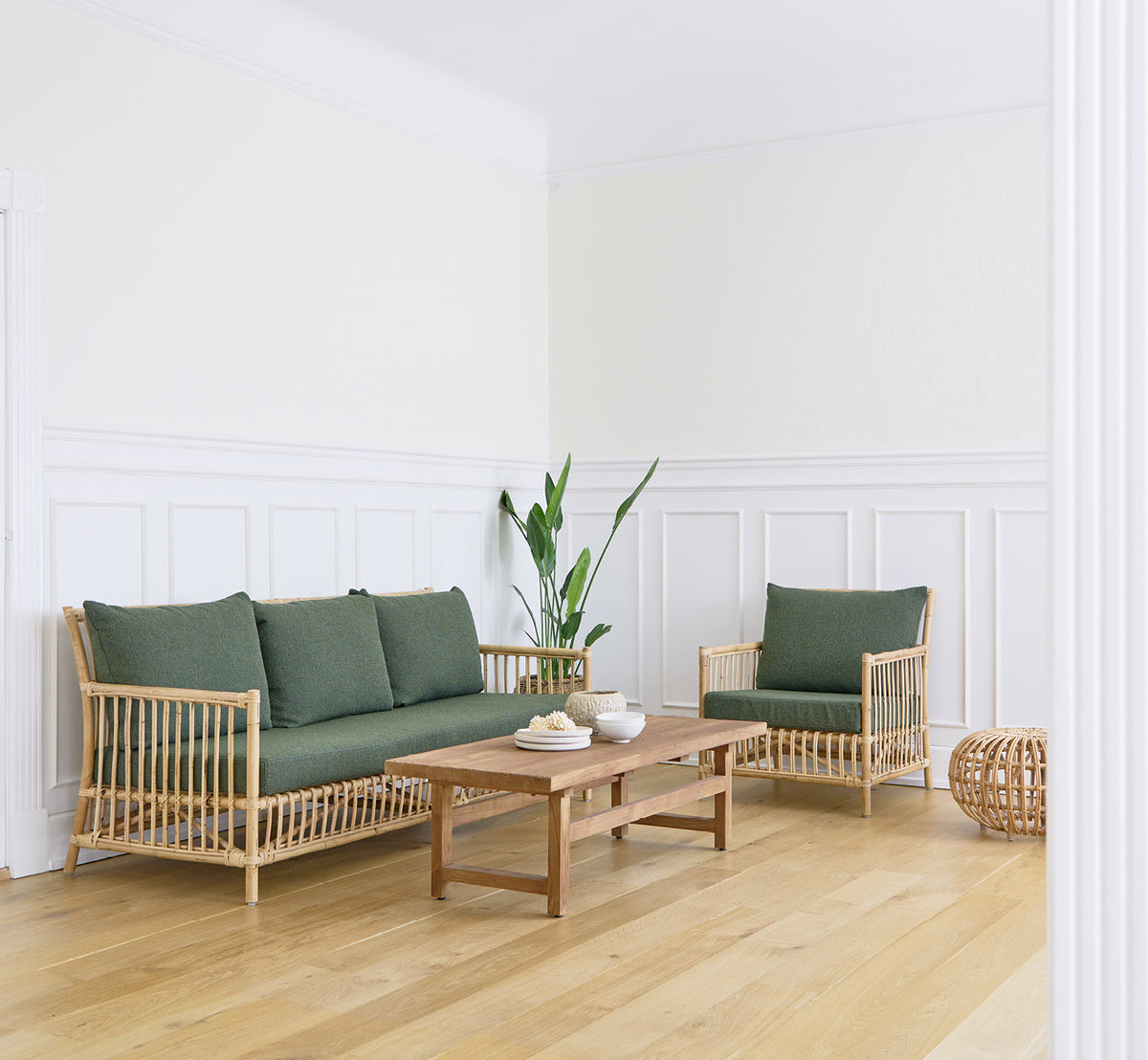 Esta es una imagen de estilo de vida de Caroline sillón lounge en natural rattan, en una luminosa sala de estar escandinava con parqué en espiga.