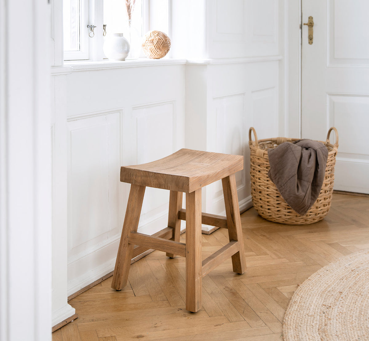 Esta es una imagen de estilo de vida de Charles taburete en teak indoor, en un interior blanco y luminoso con revestimiento de pared y parqué en.