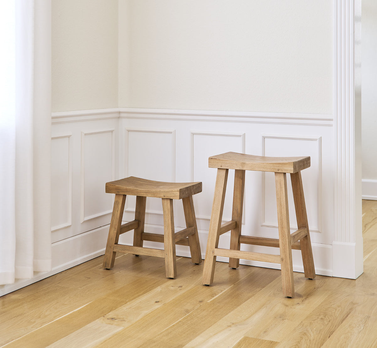Esta es una imagen de estilo de vida de Charles taburete alto en teak indoor, en un interior blanco y luminoso con revestimiento de pared y parqué en.