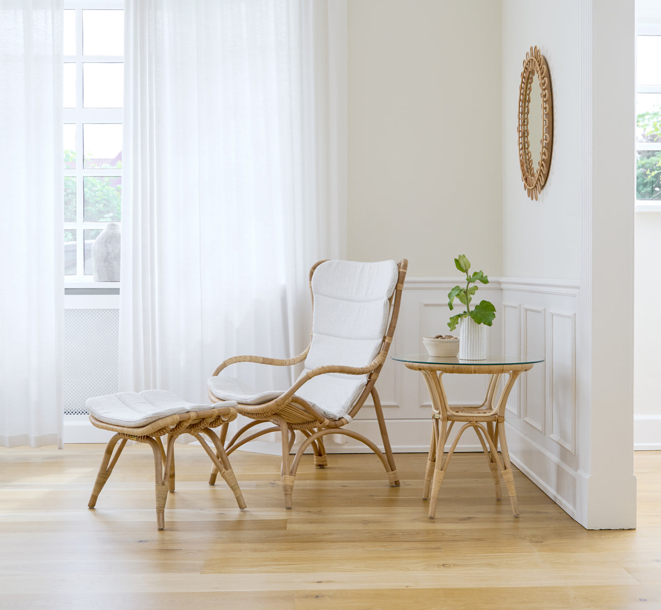 Esta es una imagen de estilo de vida de Monet Lounge Chair i natural rattan. En una habitación con paredes rosa, suelo en espiga y carrito de ratán.