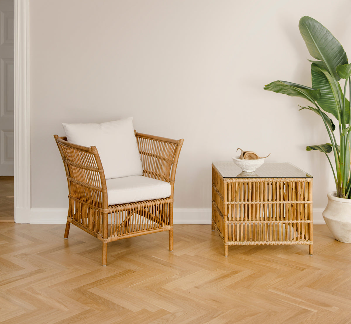 Esta es una imagen de estilo de vida de Donatello sillón lounge en antique rattan, en una luminosa sala de estar con parqué en espiga y exuberante.