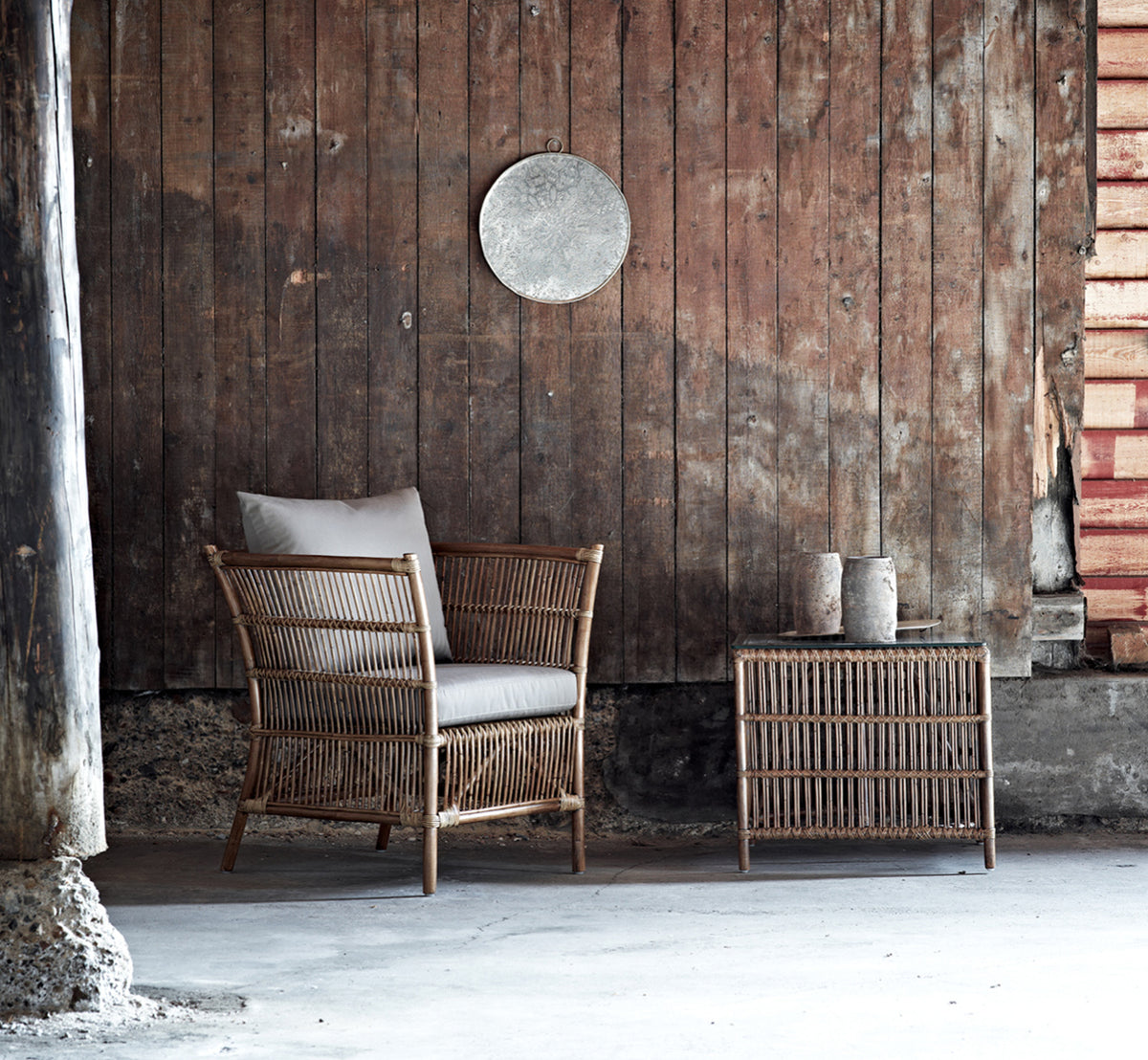 Esta es una imagen de estilo de vida de Donatello sillón lounge en antique rattan, en una luminosa sala de estar con parqué en espiga y exuberante.