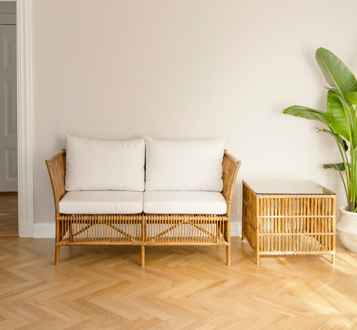 Esta es una imagen de estilo de vida de Donatello sofá de 2 plazas en antique rattan, en un interior minimalista y luminoso con parqué en espiga y.
