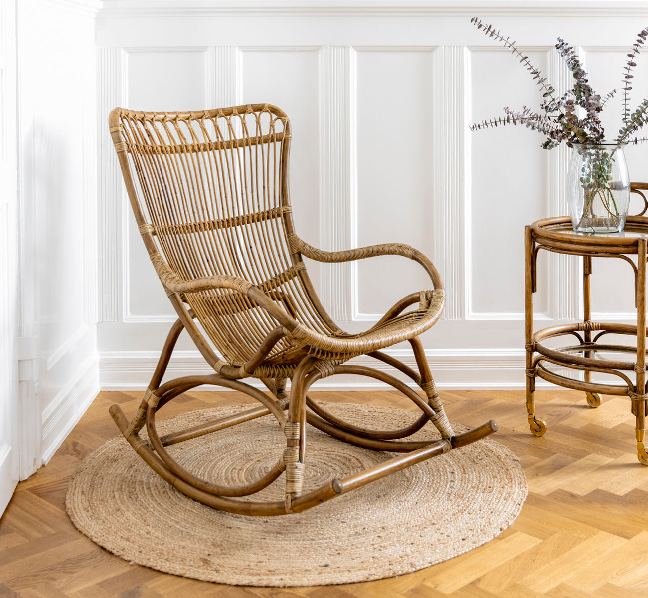 Esta es una imagen de estilo de vida de Romeo carrito en antique rattan. Estilizada con hortensias y cerámica contra una pared de ladrillo blanco.