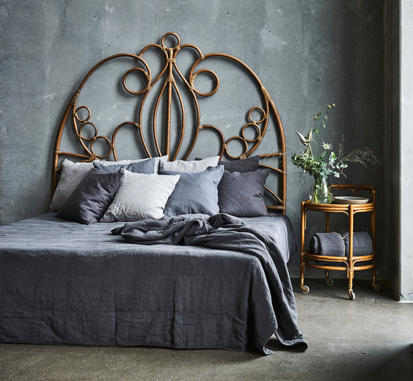Esta es una imagen de estilo de vida de Natalia cabecero en antique rattan, en un dormitorio tranquilo y luminoso con ropa de cama neutra y parqué en.
