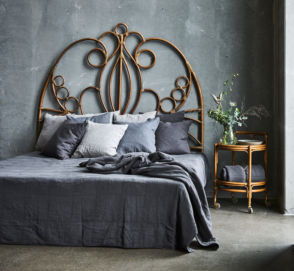 Esta es una imagen de estilo de vida de Natalia cabecero en antique rattan, en un dormitorio tranquilo y luminoso con ropa de cama neutra y parqué en.