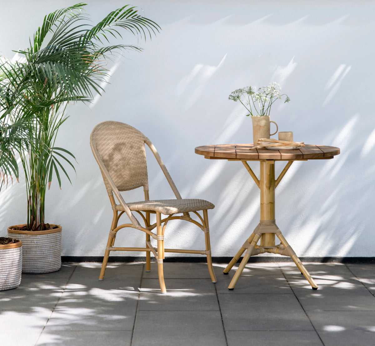 Esta es una imagen de estilo de vida de Sofie Exterior Dining Chair i almond aluminium frame natural ArtFibre. En una terraza mediterránea.