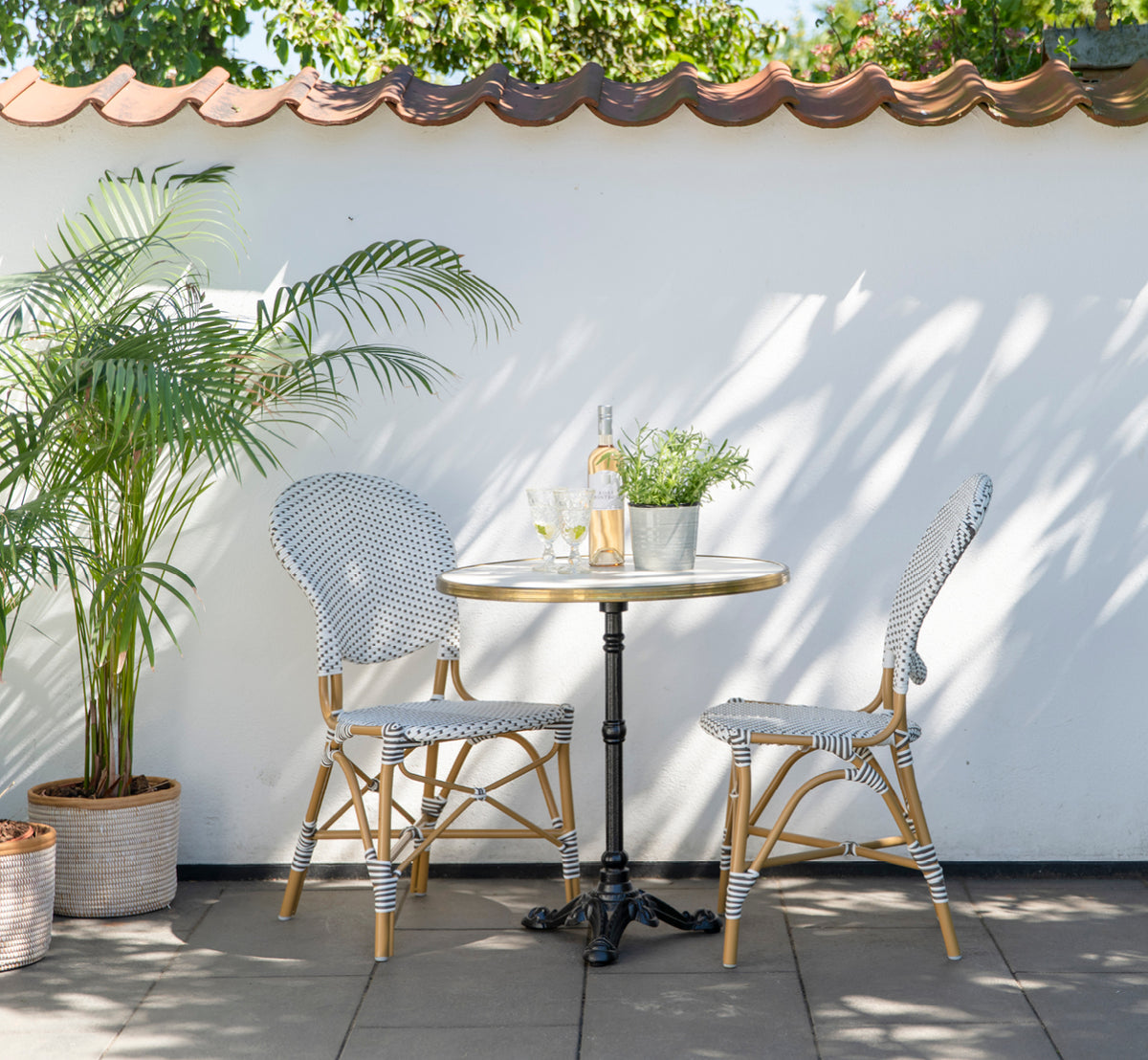 Esta es una imagen de estilo de vida de Isabell en almond aluminium frame White w cappuccino dot ArtFibre, en un exuberante patio de jardín con suelo.