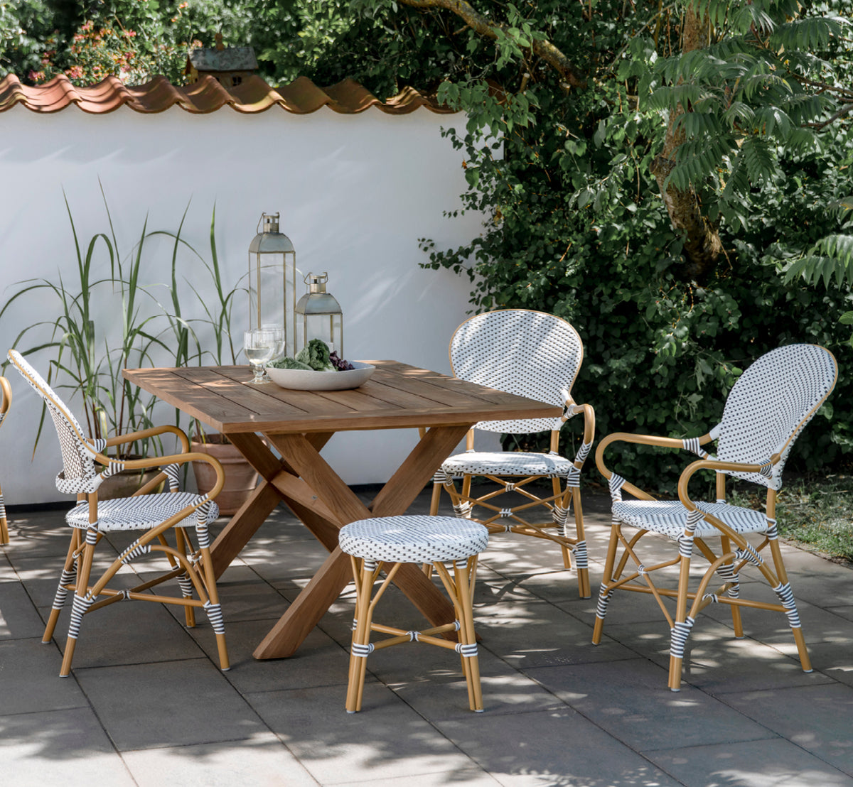 Esta es una imagen de estilo de vida de Isabell en almond aluminium frame White w cappuccino dot ArtFibre, en un exuberante patio de jardín con suelo.