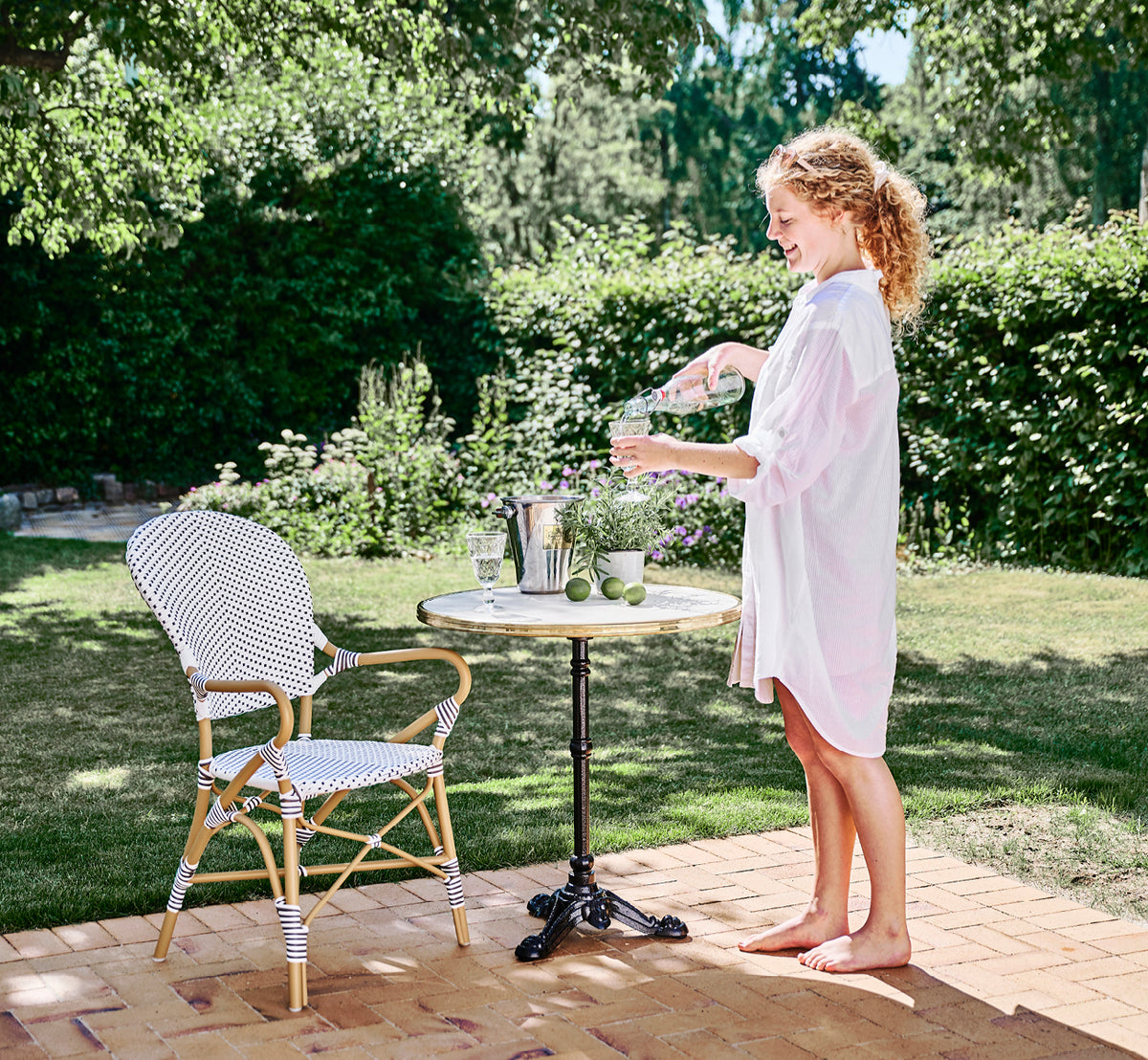 Esta es una imagen de estilo de vida de Isabell en almond aluminium frame White w cappuccino dot ArtFibre, en un exuberante patio de jardín con suelo.