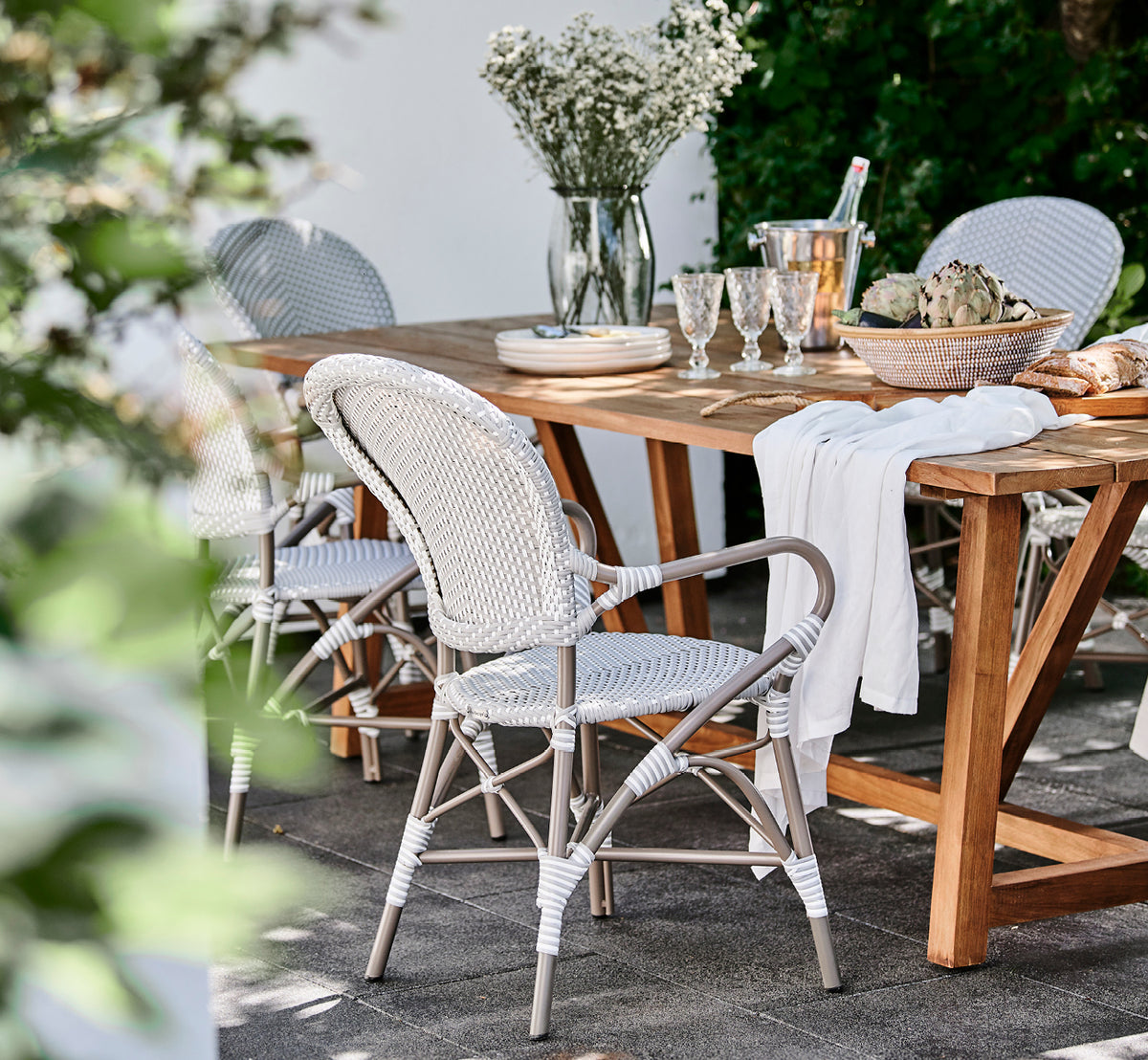 Esta es una imagen de estilo de vida de Isabell en taupe aluminium frame Grey w white dot ArtFibre, en un exuberante patio de jardín con suelo de.